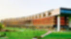 University campus landscape full of lush green lawn and a horseshoe shaped building filled with windows