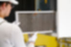 Rear image of a young while male maintenance working changing out a dirty air filter