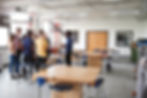 Classroom of high school students standing with their teacher around a desk