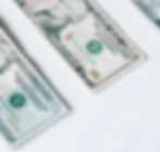 An American 20 dollar bill and ten dollar bill sitting on top of a white tabletop