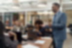 Business leader standing up and speaking to his attentive team in an open boardroom setting