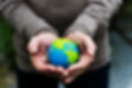 Man's hands with arms outstretched, holding a small globe representing the earth